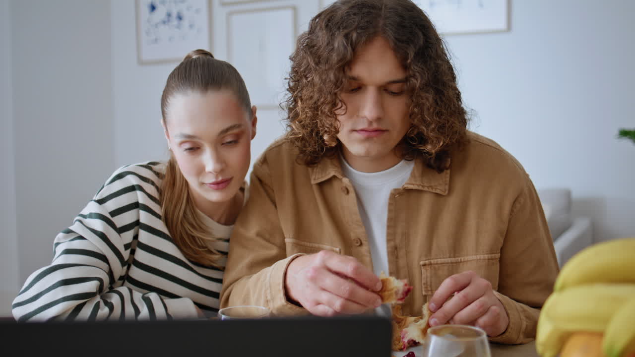 Eating spouses looking computer enjoying family breakfast in modern home closeup