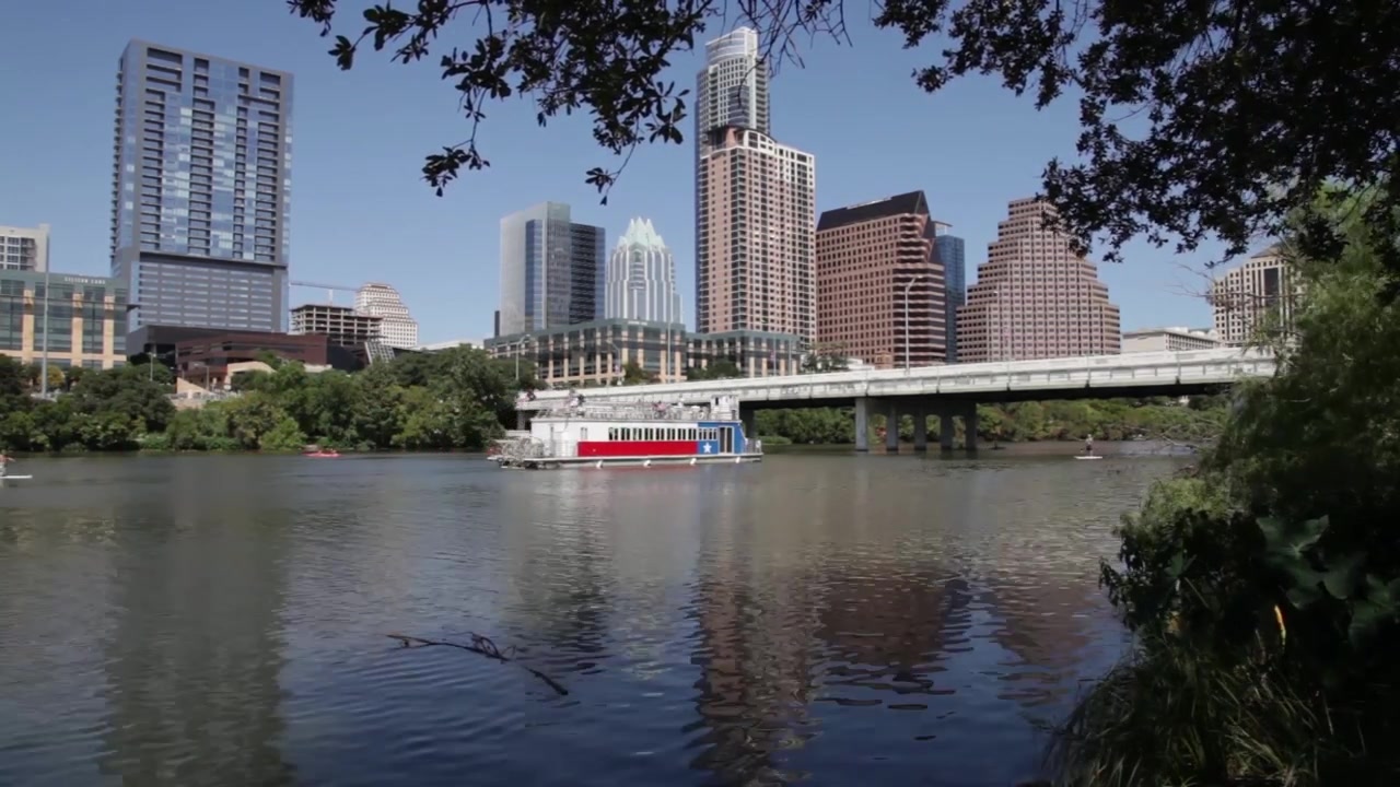 Time-lapse do rio do centro de Austin, Texas, com praticantes de stand-up paddle e um barco balsa passando.