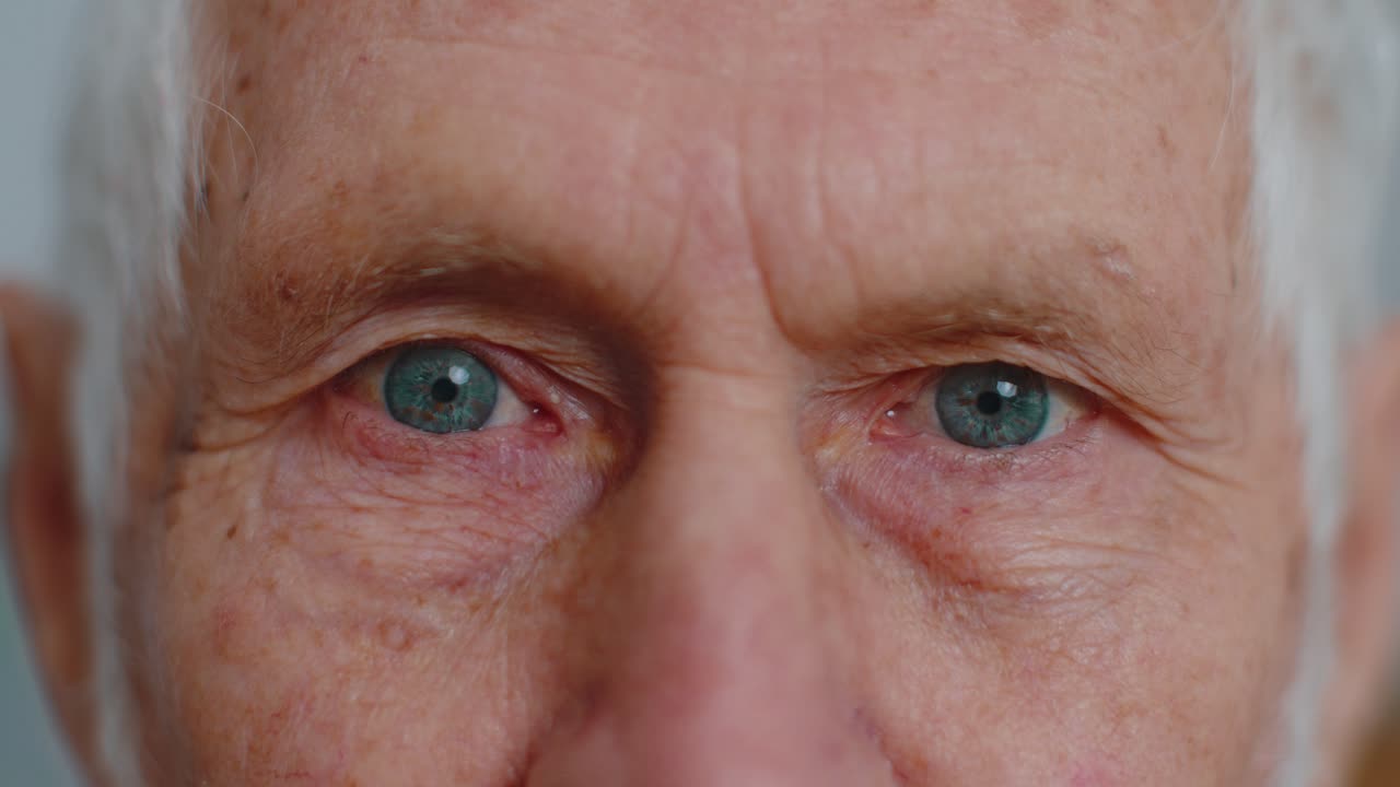 Extreme closeup macro portrait of wrinkled face old senior beautiful mans eyes looking at camera