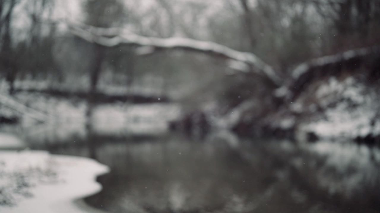 Unscharfe Winterflussszene mit sanft fallendem Schnee