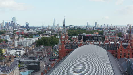 Forwards-fly-above-roof-of-St-Pancras-train-station.-Heading-to-old-brick-clock-tower.-Heavy-traffic-in-street.-London,-UK