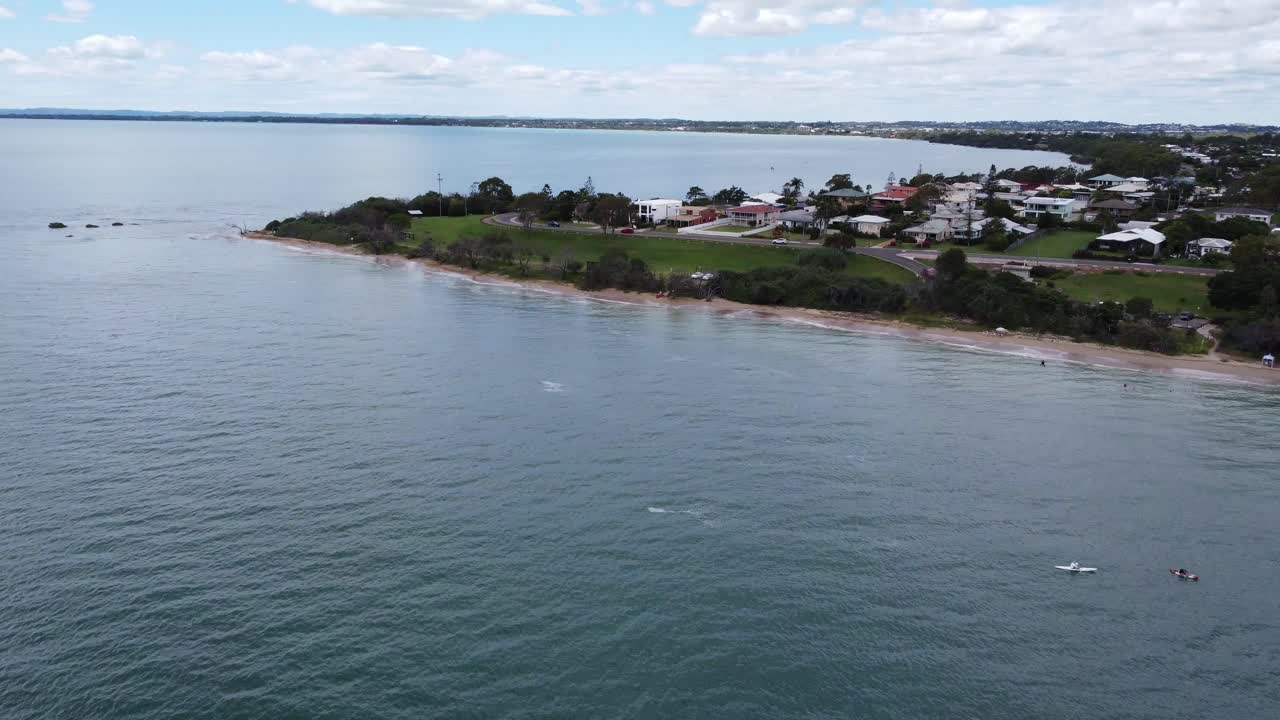 Drone stiger op over havet, en halvø i baggrunden og både nedenfor.