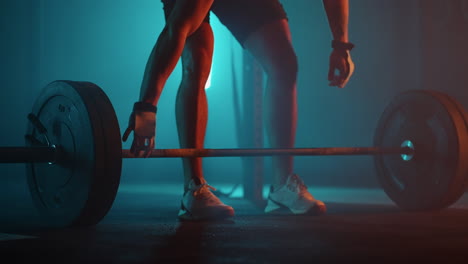 strong-man-is-approaching-to-barbell-in-dark-dramatic-gym-and-lifting-weight-legs-of-sportsman