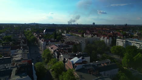 big black smoke rising over berlin, germany, on sunny day with blue sky and some clouds. unique aerial view flight descending drone