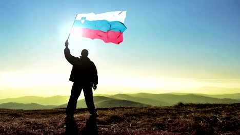 successful silhouette man winner waving slovenia flag on top of the mountain peak, cinemagraph loop background