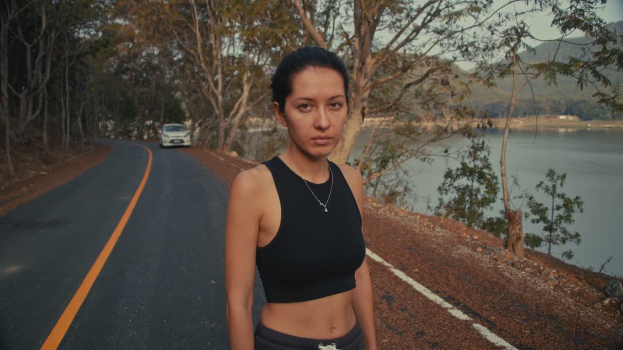 Woman Standing on a Road by a Lake