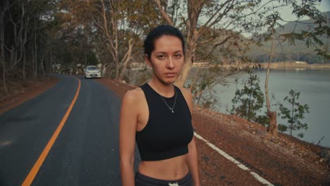 woman standing on a road by a lake