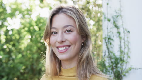 retrato de una feliz mujer biracial con cabello rubio en el jardín, cámara lenta
