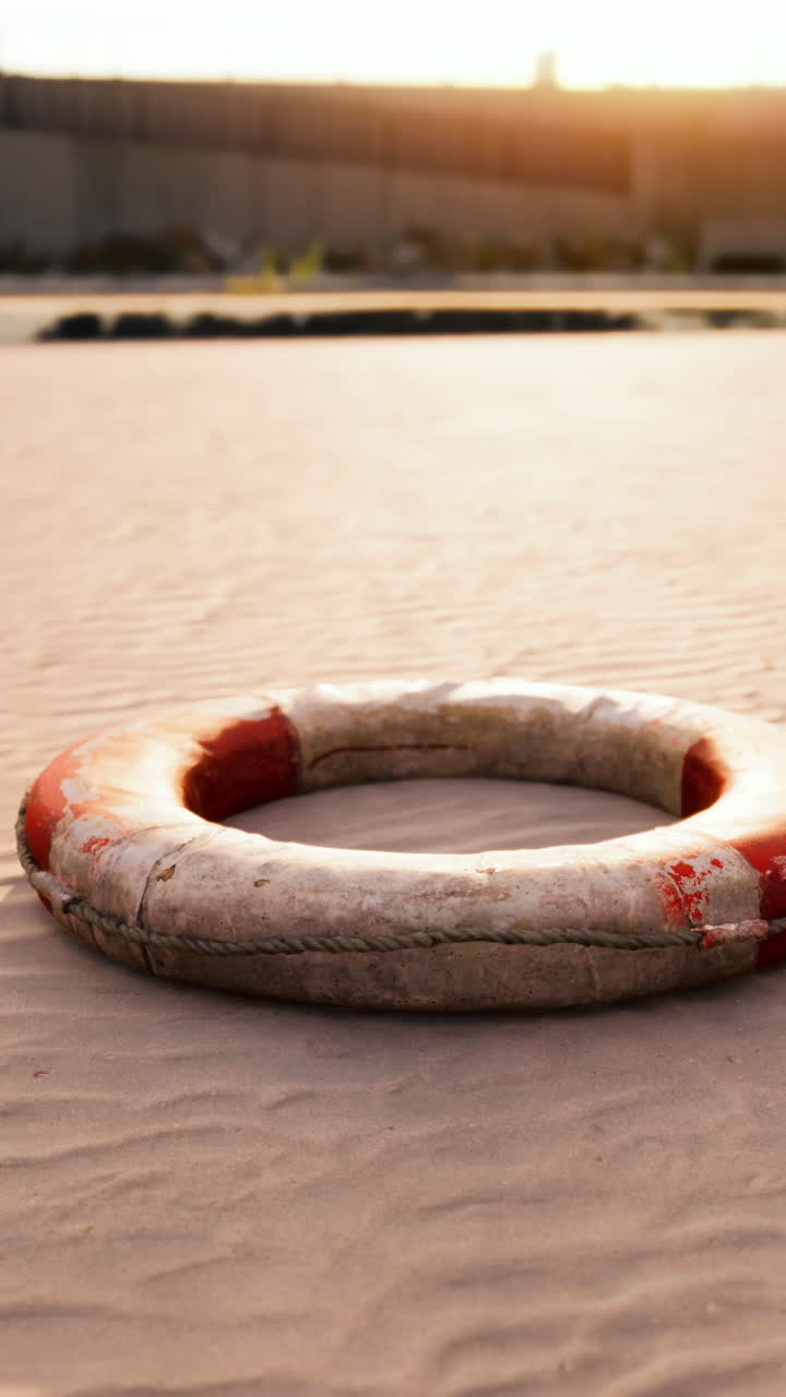 A red and white life preserver on the beach at sunset