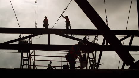 silhouetted construction workers on a steel structure