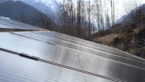 Complete-solar-panel-installation-is-producing-electricity-to-private-home---Sun-shining-on-panels-with-nature-and-mountain-background---Slow-slider-moving-from-right-to-left-close-to-panels
