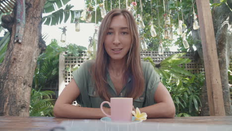 woman talking on camera in tropical cafe