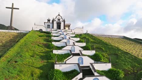 Drone-reveals-religious-architecture-in-Portuguese-Azores-Island,-white-building-with-christian-Cross