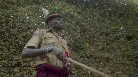 karamojong tribe african warrior in uniform with wooden stick, pointing finger outdoor in uganda