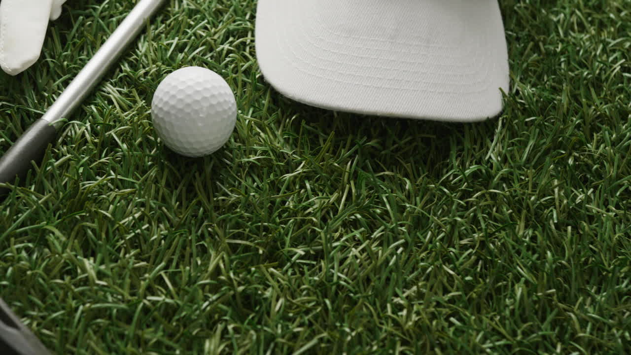 Primo piano di mazza da golf, pallina, guanto e berretto con visiera sull'erba, spazio per il testo, rallentatore