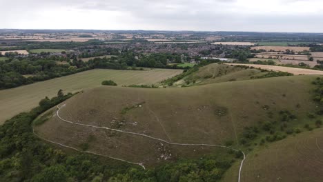 Moving-slowly-towards-hills,-cloudy-sky-aerial-shot-over-fields-in-Hitchin,-Hertfordshire,-England,-Uk