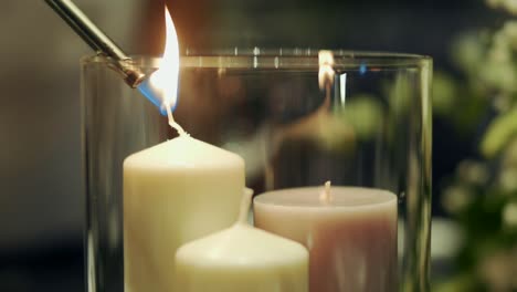 candles inside a glass candle holder being lit