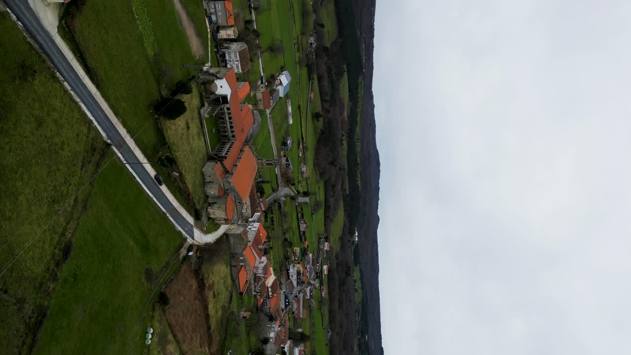 Vertical establishing orbit around Santa Maria de Xunqueira monastery under cloudy sky