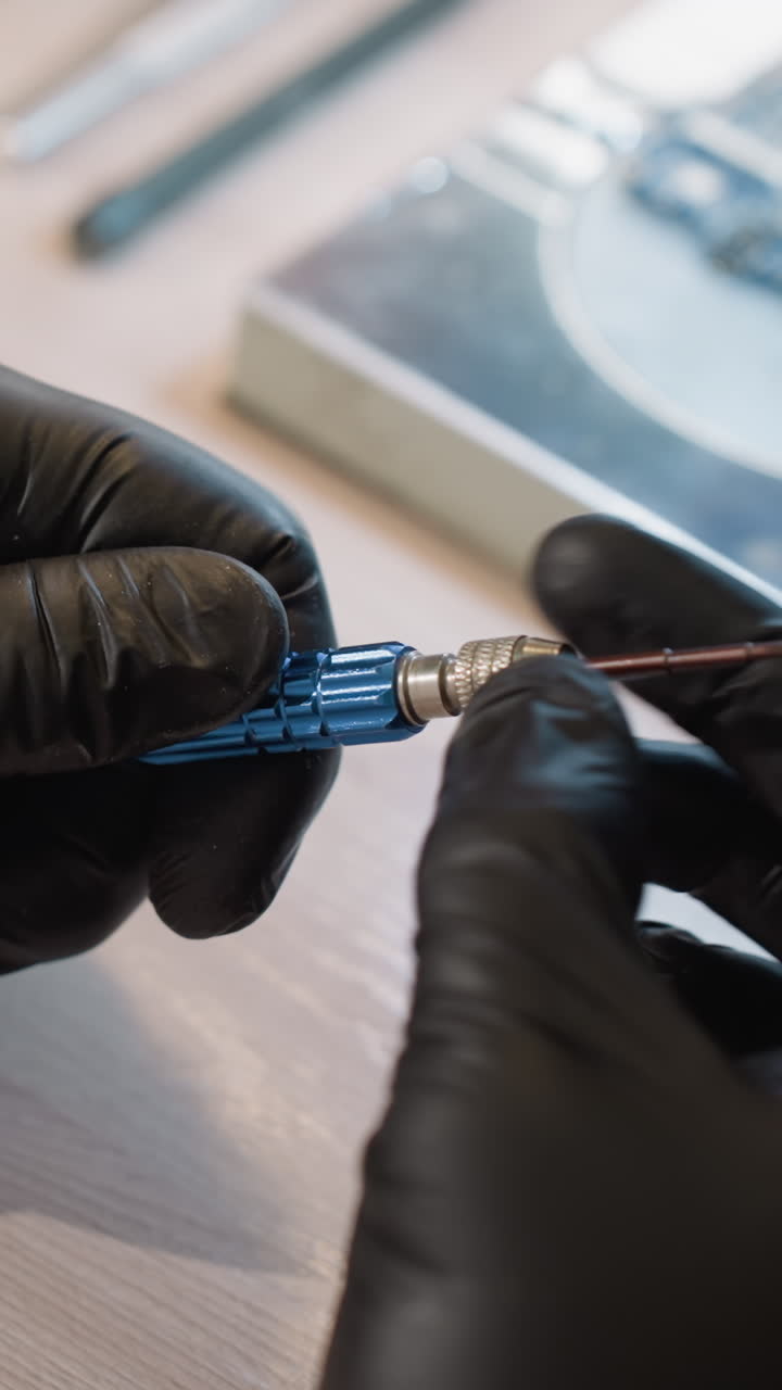 vista de cerca de las manos de un técnico con guantes negros, girando delicadamente un tornillo azul, con una placa de circuito en el fondo