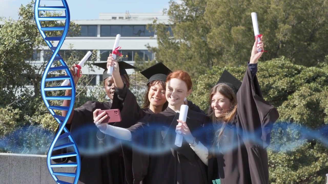 Laureati che allungano il telefono per scattare un selfie per la laurea nel campus, mentre tengono i diplomi con un'elica di DNA e una forma d'onda