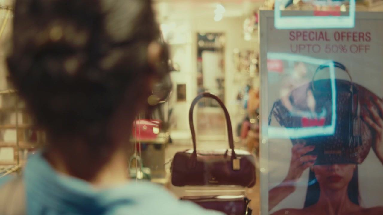 Woman browsing a retail shop window displaying handbags and merchandise in Goa, India, with reflections and a special offer sign creating a candid shopping scene.