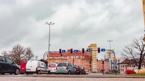 a time-lapse of traffic and pedestrian movement at a traffic intersection in bydgoszcz, poland on a cloudy day.