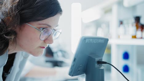 teenage girl in lab looking at microscope screen