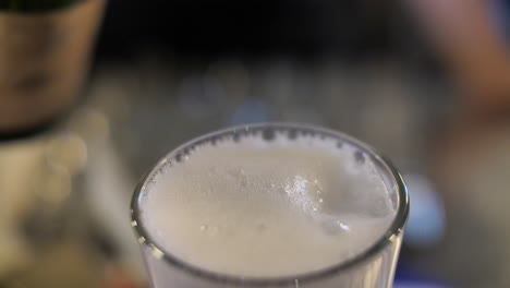 bartender pouring champagne to cocktail to glass, close up