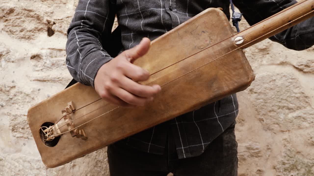 모로코의 에사우이라에서 모로코인 남자가 전통적인 모로코 브리를 연주하고 있습니다.