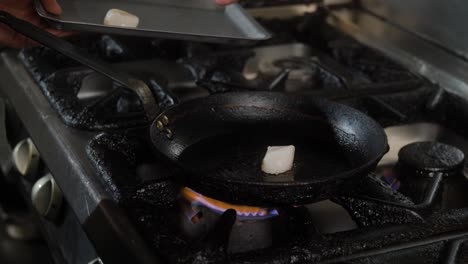 chef adds scallops to a cooking pan