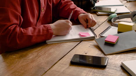 top view of blond boy with of a study group writting sitting at table and talking with othes mates