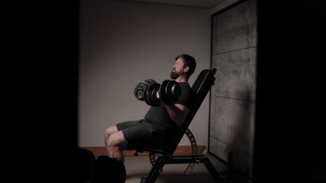 Sitzende-Hantel-Bizeps-Curls,-Filmische-Beleuchtung,-Weißer-Mann-In-Schwarzer-Sportkleidung