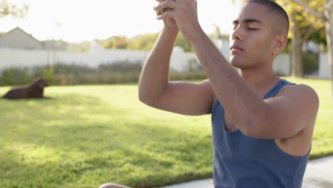 Fokussierter-Biracial-Mann-Praktiziert-Yoga-Meditation-Im-Sonnigen-Garten,-Zeitlupe