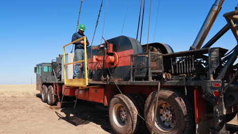 worker stands at the deck of a huge truck with tower for oil/gas drilling. equipment for boring natural resources.