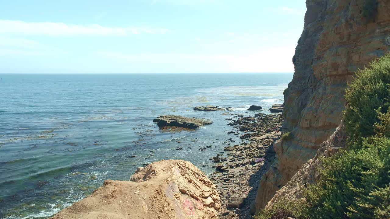 toma amplia, olas rompiendo tranquilamente en la costa rocosa en la costa de california en un día soleado