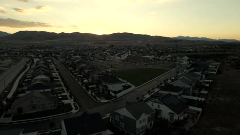 Puesta-De-Sol-Detrás-De-Las-Montañas-Con-Un-Pintoresco-Barrio-Suburbano-En-El-Valle---Paralaje-Aéreo