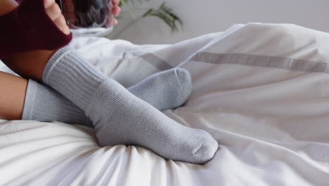 relaxing on bed, woman wearing cozy grey socks, enjoying home day at home