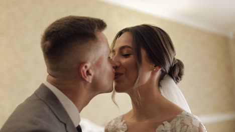 Newlyweds-young-caucasian-bride-and-groom-first-meeting-at-wedding-day,-making-a-kiss-indoors