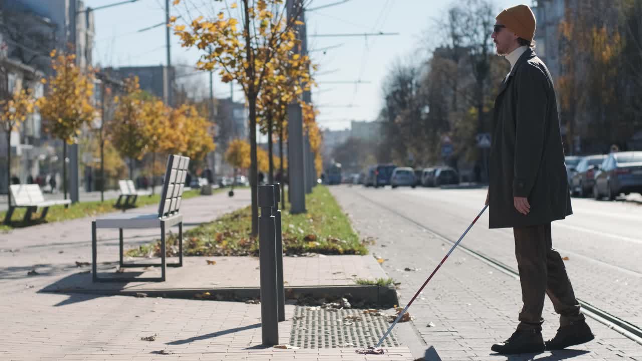 외로운 눈먼 남자가 촉각 타일을 감지하여 보행자가 안전한 도로를 건너고 있습니다.