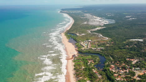 aerial view of the waves, beach, a small river and the palm trees area in a cloudy day, imbassai, bahia, brazil