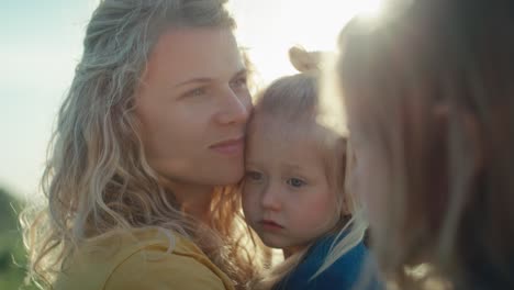 Close-up-of-mom-with-two-daughters-spending-time-at-the-meadow.