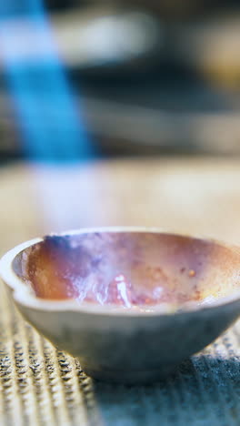 cu: old gold rings melt in small crucible with torch flame on table with asbestos sheet in jewelry workshop closeup