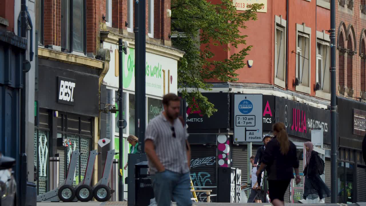 Urban street scene with people walking, cycling, and interacting in natural daylight, handheld camera movement