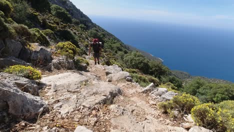 a young fit male hiker walking uphill on a steep climb along the mediterranean sea in turkey