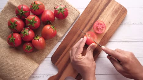 vista superior de la mano del hombre cortando tomate en la tabla de cortar