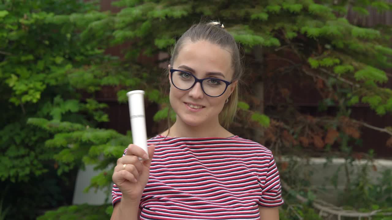 A girl with glasses holds a jar of vitamins in her hand and waves it. Maintaining immunity. Healthy lifestyle. 4k