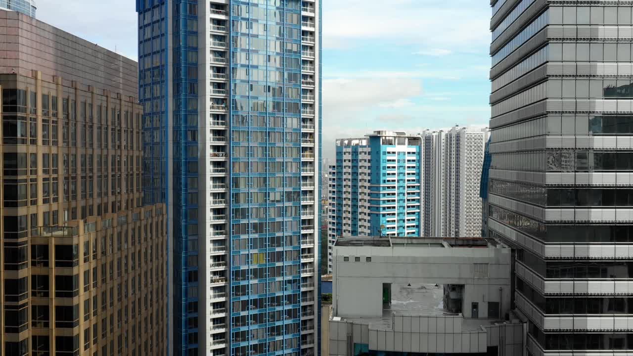Drone flies between buildings in Manila, the capital of Philippines. There is buisiness and residential buildings everywhere - aerial view
