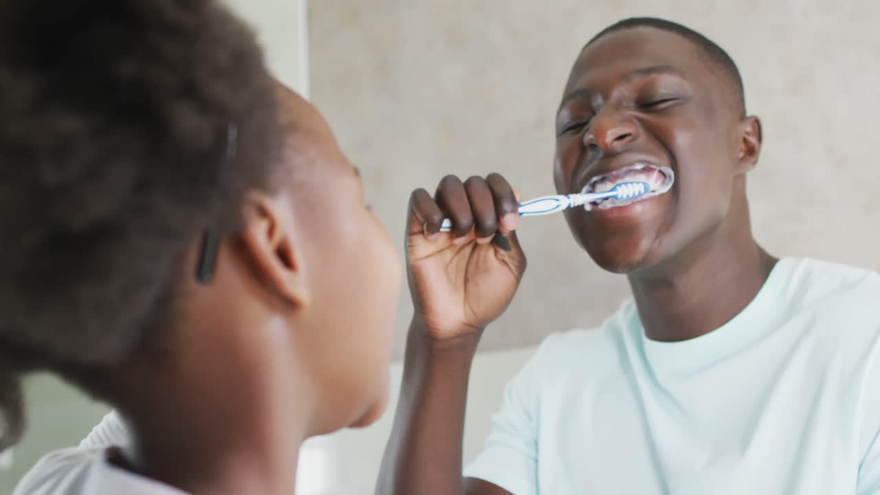 Video of african american father and daughter brushing teeth