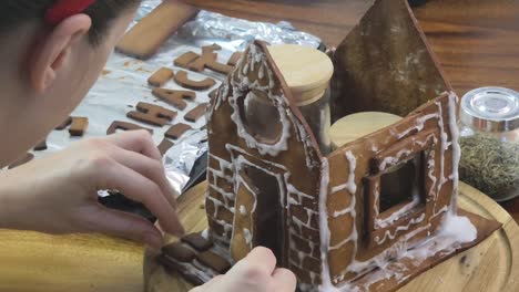 person decorating a gingerbread house