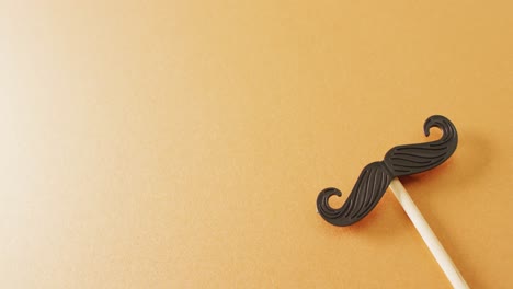 Video-of-false-moustache-on-stick-on-yellow-background-with-copy-space